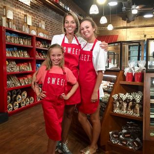 Mom and daughters in aprons smiling in shop