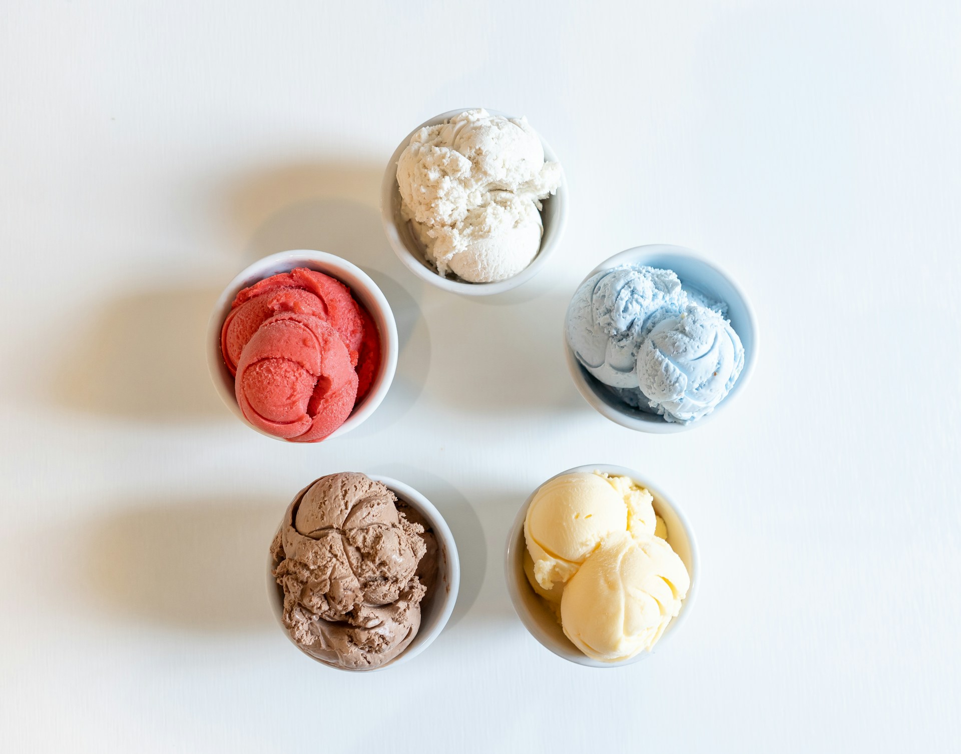Multiple ice cream scoops in bowls as seen from overhead.